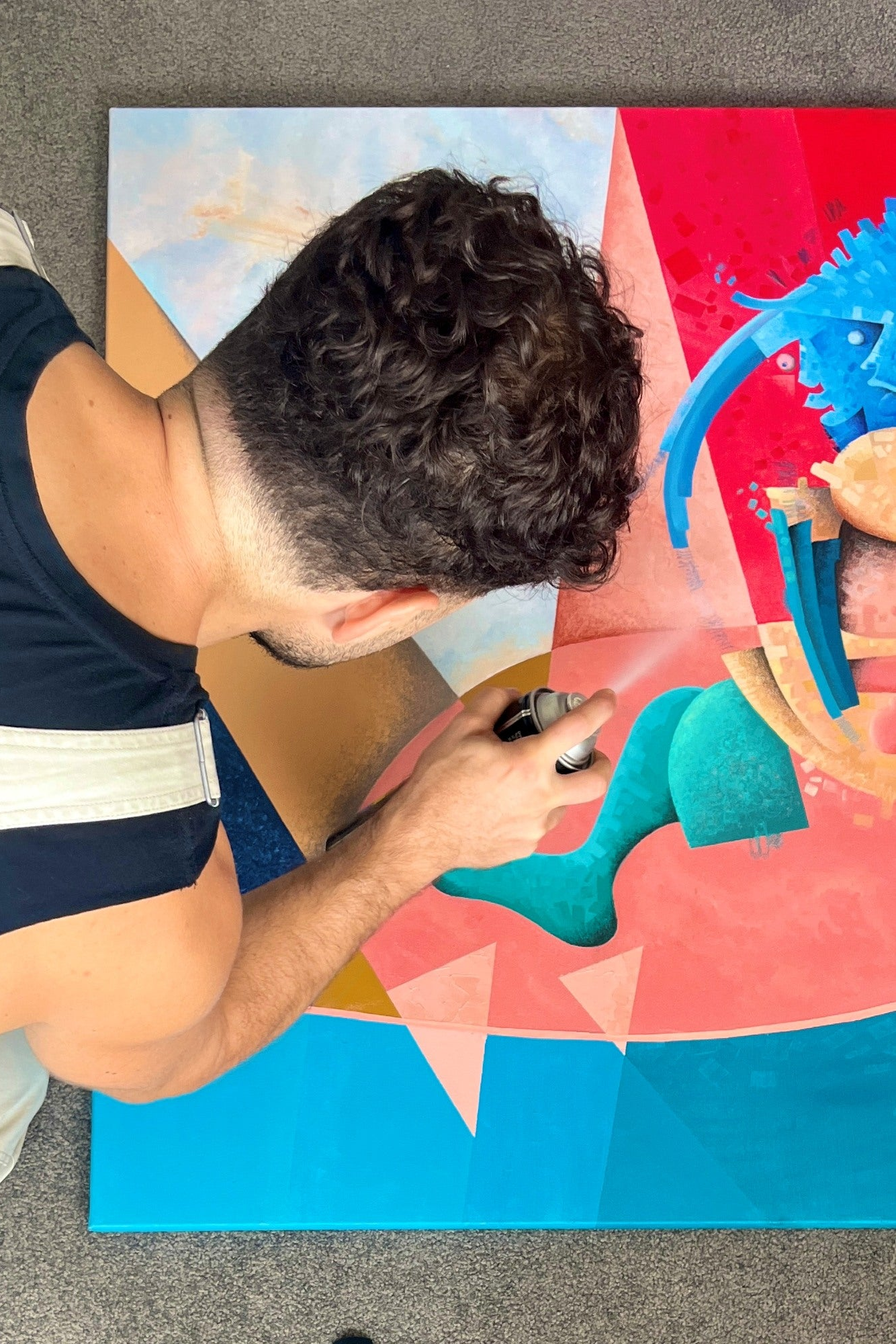 Person using a tool on a colorful abstract painting